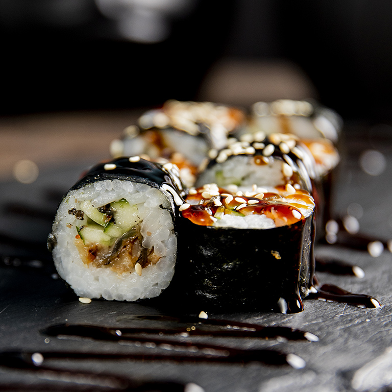 maki roll with cucumber served with sauce and sesame seeds